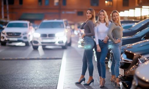 drei Frauen in Jeans und High Heels warten auf den Fahrservice